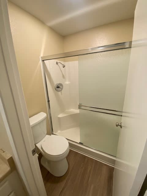 A white toilet with a glass shower door in a small bathroom.