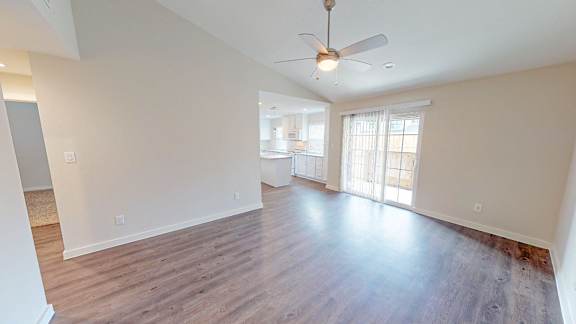 Spacious living room with a ceiling fan vaulted ceilings.