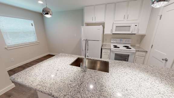 A kitchen with a granite countertop and white cabinets.
