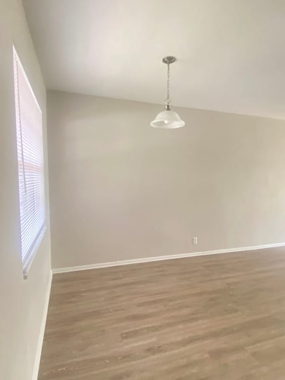 A room with a light hanging from the ceiling and a window on the left. at Imperial Gardens Apartments, Clearwater, FL