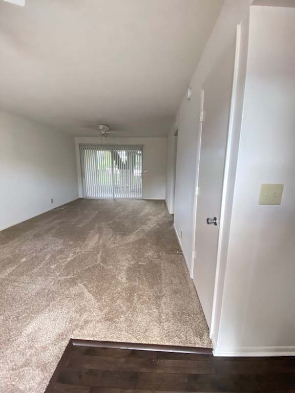 A room with a carpeted floor and a door. at Imperial Gardens Apartments, Clearwater, Florida