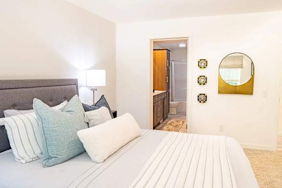 bedroom with a bed, pillows, a lamp, and a mirror.