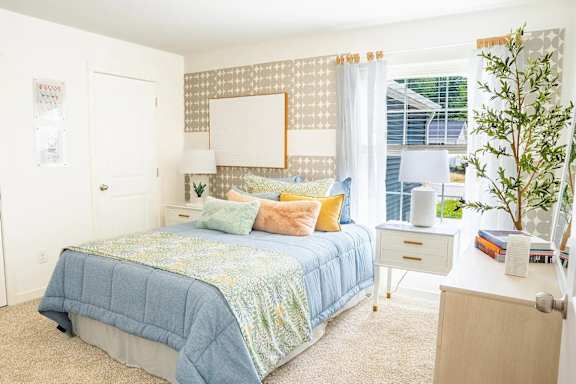 bedroom with a bed, nightstand, and a plant.