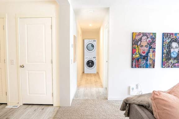 hallway with a washing machine in the middle and two paintings on the wall.