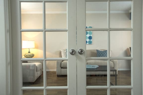 Interior French doors to living room in one bedroom apartment in Las Vegas near UNLV with white trim and silver knobs.