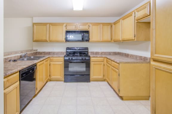 kitchen with wood cabinets and black appliances at Toscana Apartments, California, 91406