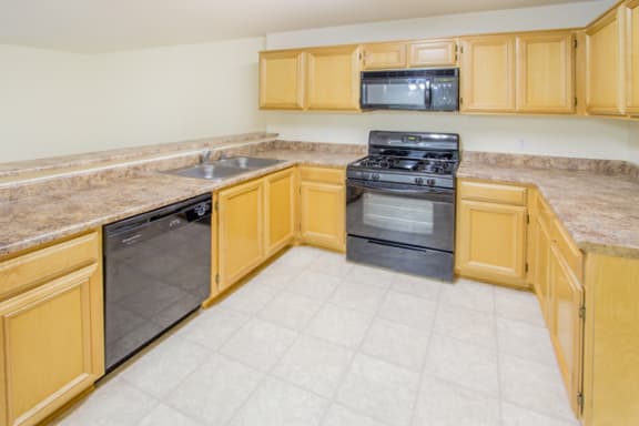 kitchen with wood cabinets and black appliances at Toscana Apartments, Van Nuys, CA