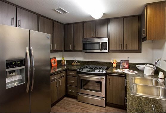 a kitchen with a stainless steel refrigerator freezer and a stove top oven at Legacy Apartments, Northridge