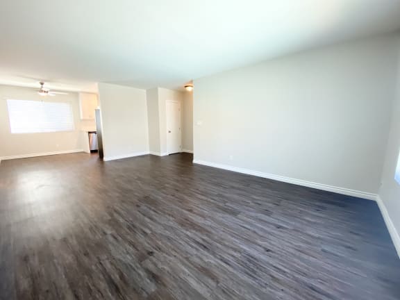 an empty living room with wood flooring and white walls.