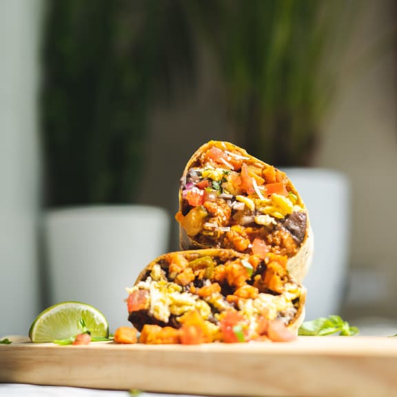 a photo of two stuffed sweet potatoes on a wooden cutting board with a slice of lime