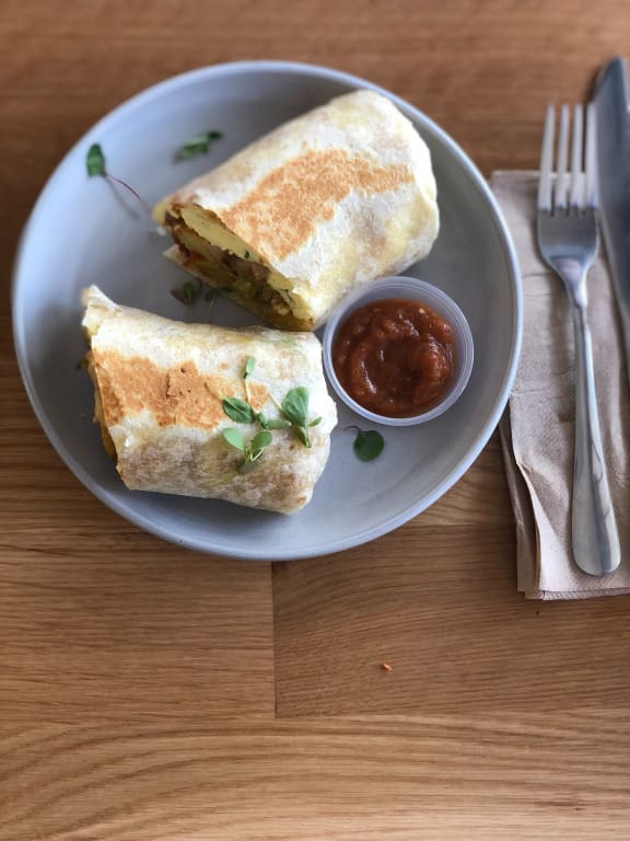 a burrito on a plate with a side of salsa