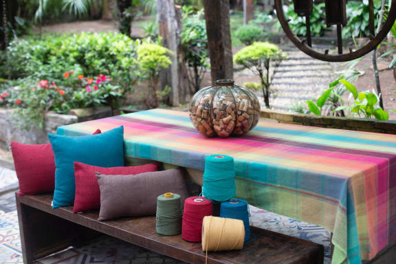 a table with a colourful tablecloth and colourful cushions