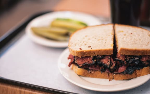 a roast beef sandwich with pickles on the side