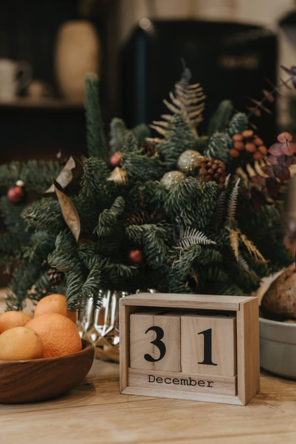 a table with a christmas tree and oranges in a bowl