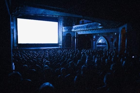 a large crowd watches a movie on a dimly lit screen