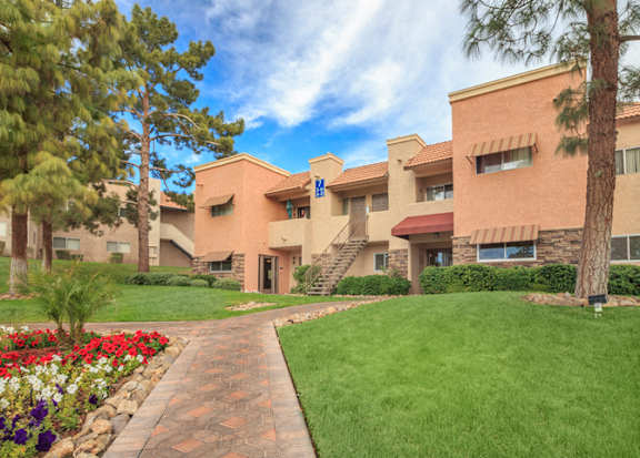 a building with a green lawn and flowers in front of it at Desert Bay Apartments, Laughlin