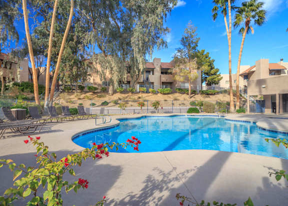 a large swimming pool with trees and buildings in the background at Desert Bay Apartments, Laughlin