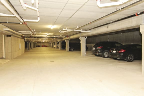 A long, empty parking garage with cars parked on the right side.