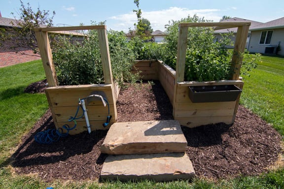 A garden with a watering can and two wooden planters.