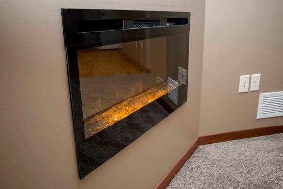 A modern fireplace with a glass front and a warm glow inside.
