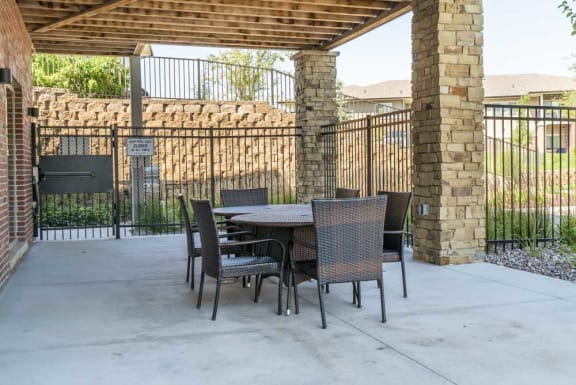 A patio with a table and chairs is enclosed by a black metal fence.