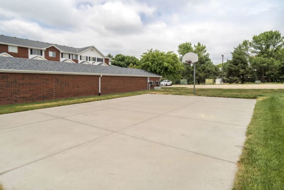 A basketball court is located in front of a brick building.