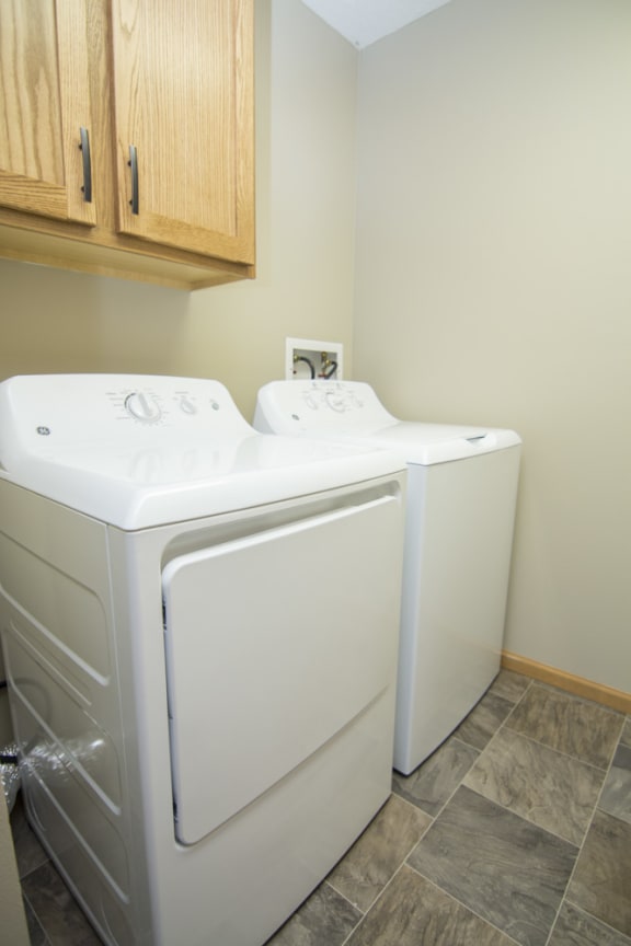 Side by side washer and dryer with cabinets for storage in laundry room Swimming pool with sun tanning loungers at Williamsburg Park Apartments in South Lincoln, Nebraska