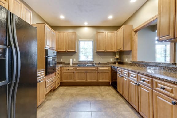 A kitchen with wooden cabinets and a black refrigerator.