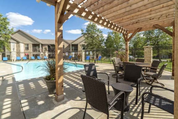 A patio with a table and chairs overlooking a pool.