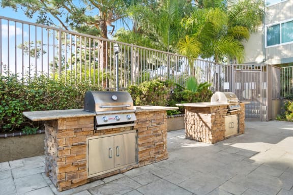 an outdoor kitchen with a grill and a table with a chair