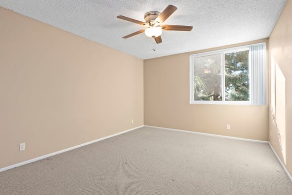 an empty room with a ceiling fan and a window
