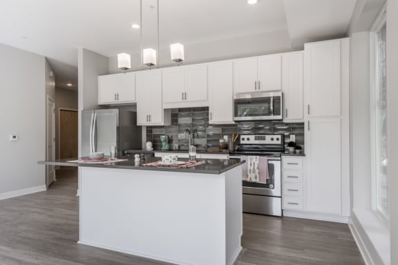 Kitchen with island with white cabinets and dark grey counters