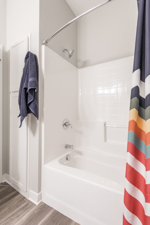 White tub shower combo  with towels hung nearby