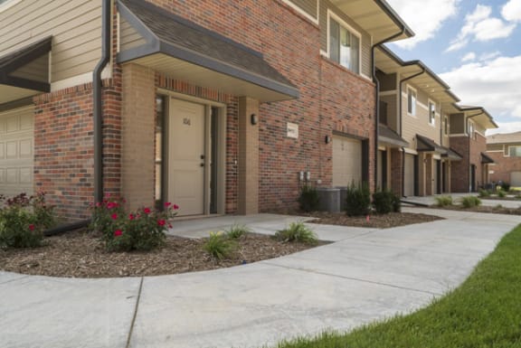 A row of houses with a white door and a brown brick wall.