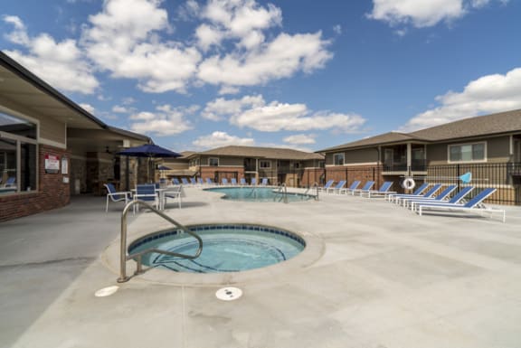 A swimming pool area with sun loungers and a building in the background.