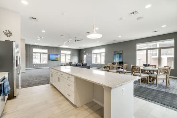 A kitchen with a refrigerator, island, and dining table.