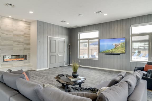 A modern living room with grey couches and a stone fireplace.