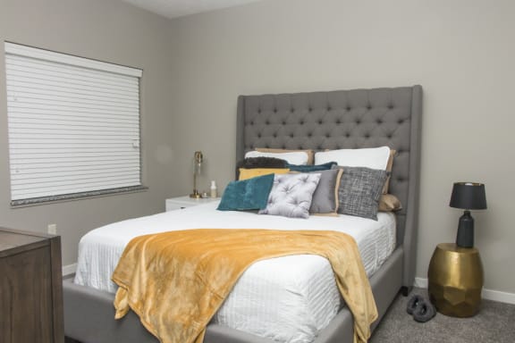 A bedroom with a bed covered in a white comforter and a yellow throw.