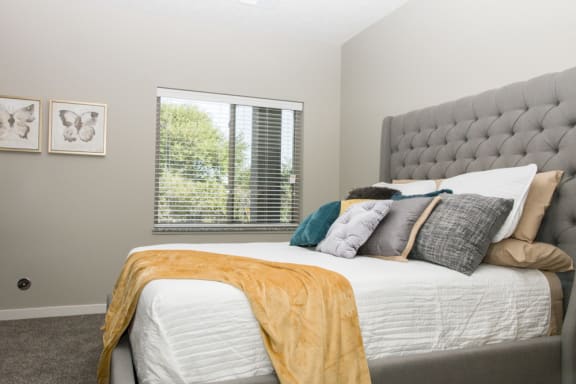 A bedroom with a large bed and a window with blinds.
