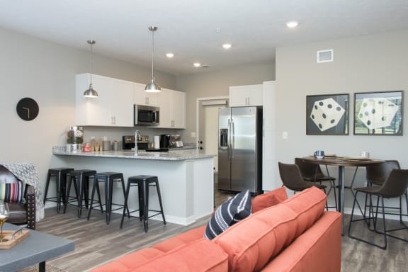 A kitchen with a bar and a dining table with chairs.