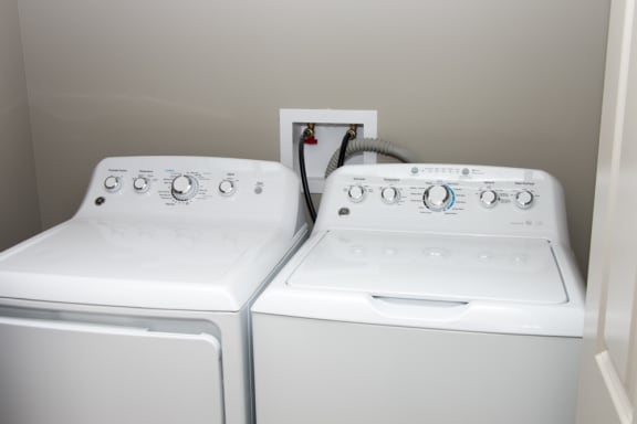 Two white front loading washing machines in a laundry room.