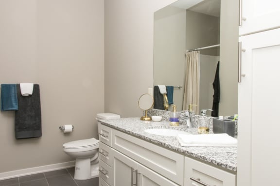 A bathroom with a toilet, sink, and mirror.