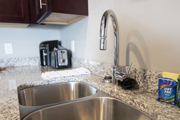 Open kitchen with granite countertops and dark brown cabinets at 360 at Jordan West in West Des Moines, IA