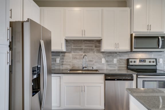 Kitchen with dark countertops, matching stainless steel appliances, and white cabinets at Ascend at Woodbury in Woodbury, MN