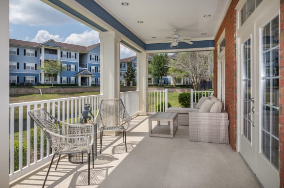 A balcony with a chair and table is shown at Magnolia Village Apartments, Jacksonville, 32207