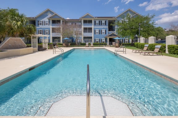 A large swimming pool in front of a multi-story apartment building at Magnolia Village Apartments, Florida