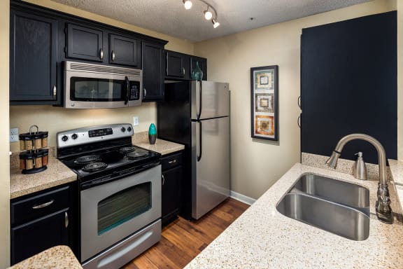 kitchen in model apartment with stainless steel appliances and granite countertops