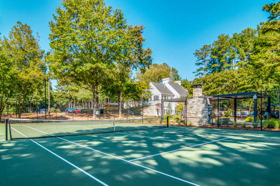 a tennis court with trees and a house in the background
