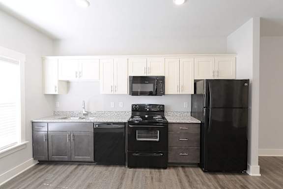 A kitchen with black appliances and white cabinets. at McHenry Square Apartments, Georgia, 30909