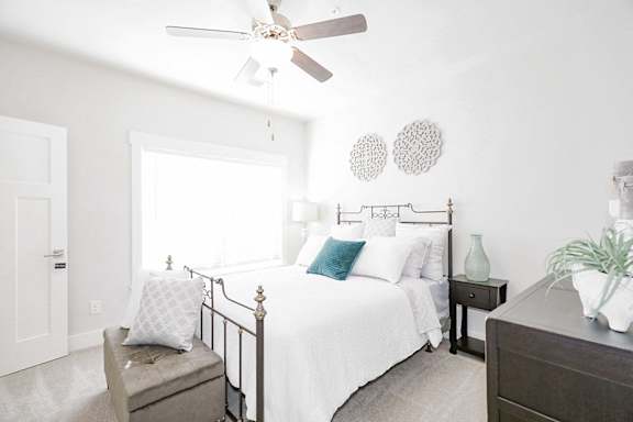 A bedroom with a bed, nightstand, and a ceiling fan at McHenry Square Apartments, Augusta, Georgia